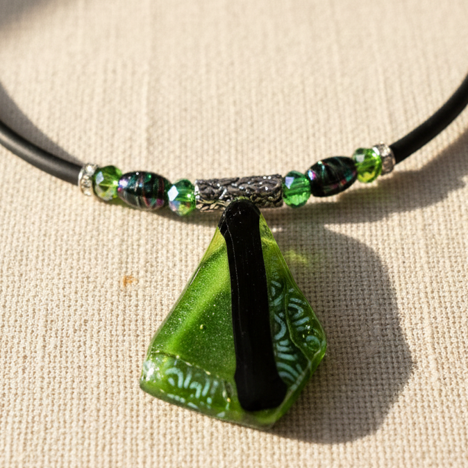 Green dichroic glass pendant necklace on black cord with green crystal beads and silver accents, 16 inches.