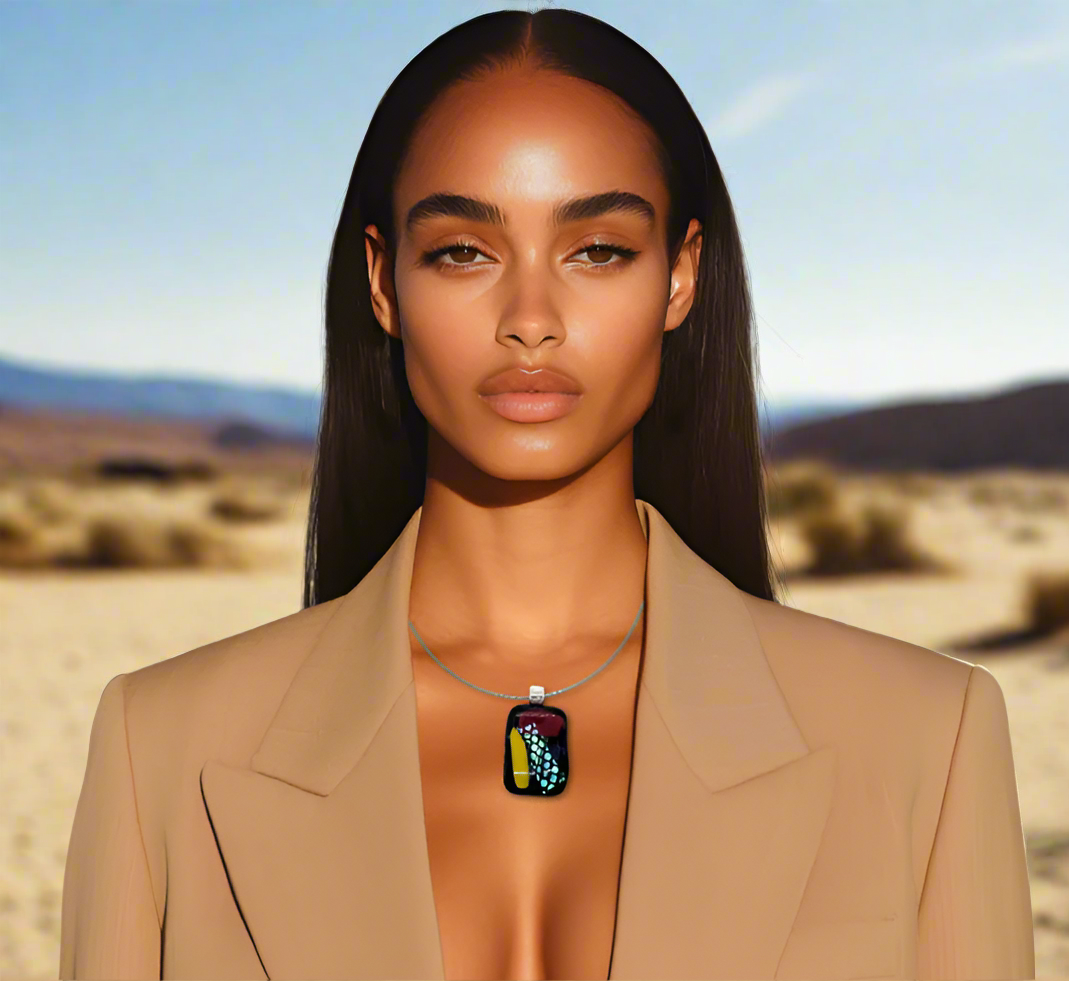 Woman wearing a beige blazer with a necklace featuring a colorful pendant against a desert background