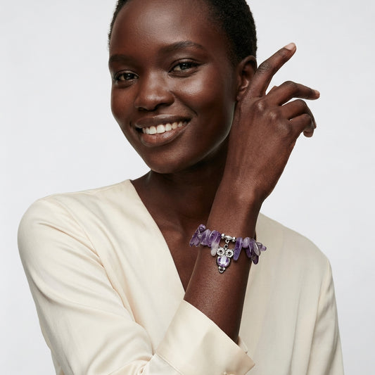 Amethyst gemstone stretch bracelet with deep purple stones and a crystal owl charm on the wrist.