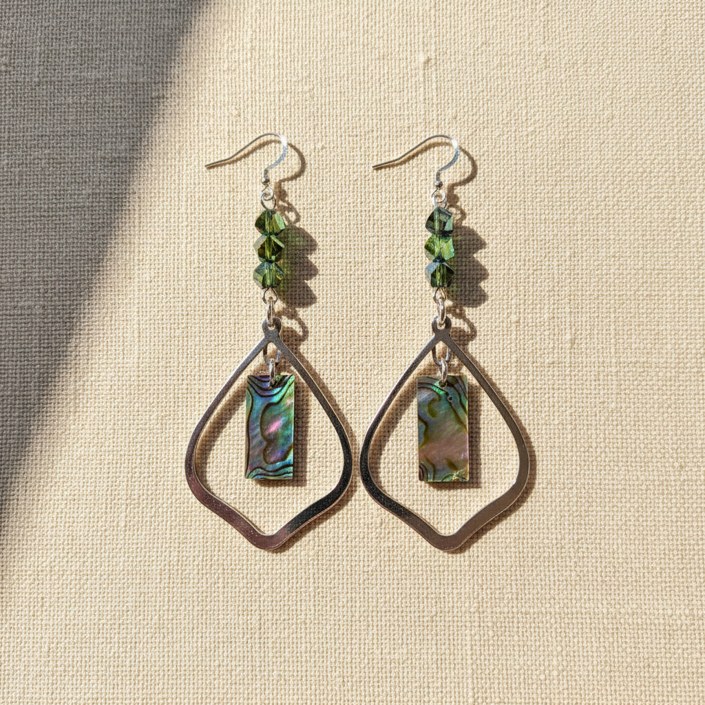 A pair of drop earrings displayed on a black velvet jewelry bust. Each earring has a silver-tone paperclip chain, three iridescent faceted beads, and a teardrop-shaped piece with a rectangular iridescent shell inlay.