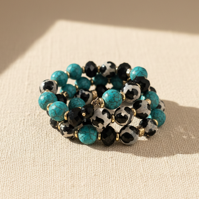 Stack of beaded bracelets with turquoise and black beads on a beige surface