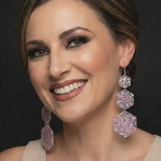 Model wearing acrylic hexagon drop earrings.  She is touching earrings and moving her head.  