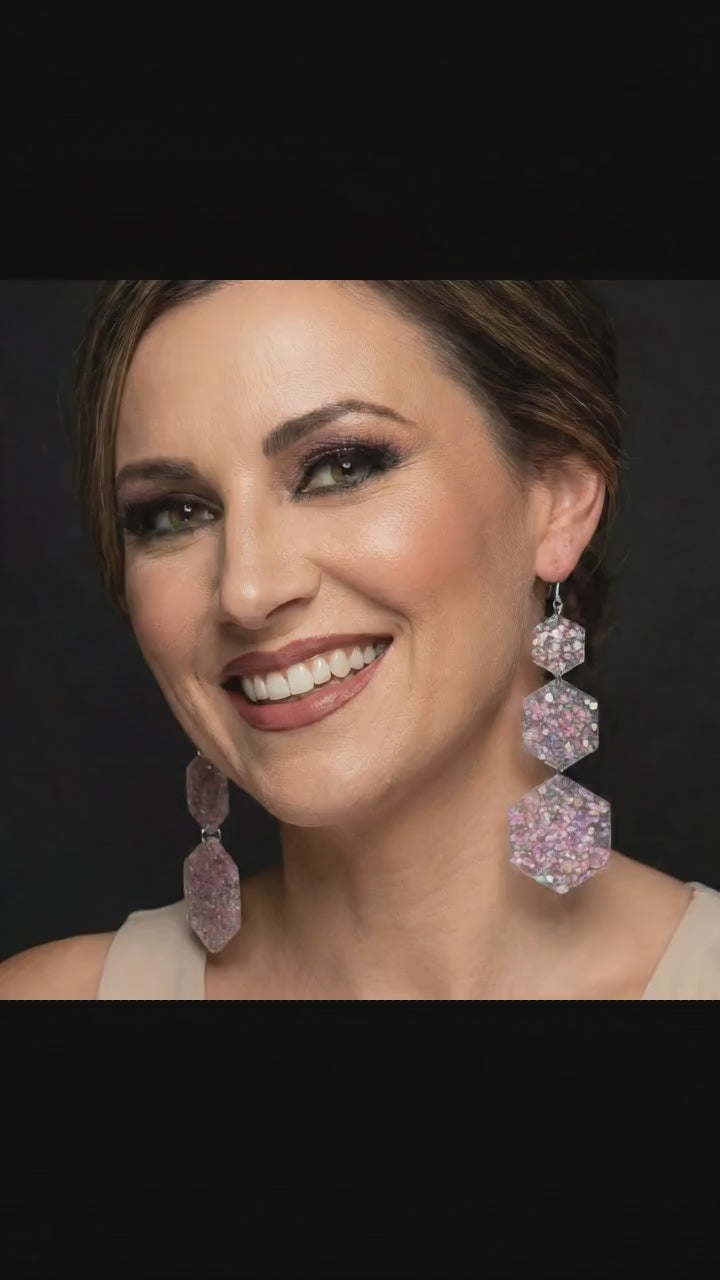 Model wearing acrylic hexagon drop earrings.  She is touching earrings and moving her head.  